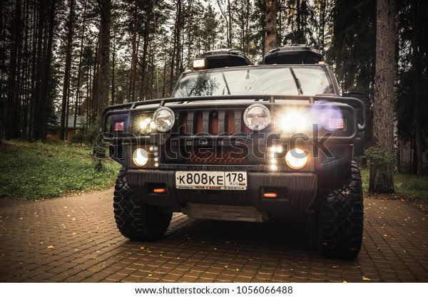Saint-Petersburg, Russia - October 8, 2017: Hummer H2\
car stands on rural parking lot in Russian countryside, close up\
front view, headlights\
on