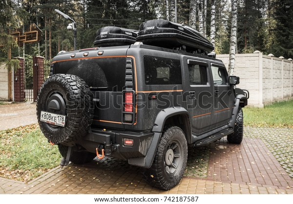 Saint-Petersburg, Russia - October 8, 2017: Black\
Hummer H2 car stands on rural parking lot in Russian countryside,\
rear view