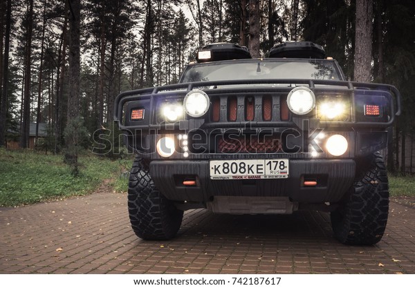 Saint-Petersburg, Russia - October 8, 2017: Black\
Hummer H2 car stands on rural parking lot in Russian countryside,\
close up front view, headlights\
on