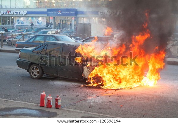 SAINT-PETERSBURG, RUSSIA-NOVEMBER 11: Burning\
car is on city street with used extinguishers on November 11, 2012\
in Saint-Petersburg, Russia. Self-ignition car wiring. No one was\
injured.