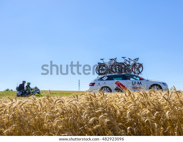 SAINT-QUENTIN-FALLAVIER,FRANCE - JUL 16: The\
technical car of IAM Cycling Team and an official bike driving in a\
wheat plain during the stage 14 of Tour de France\
2016.
