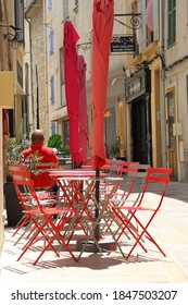 SAINT-REMY-DE-PROVENCE, FRANCE - 05282019: Lovely Caffe Accented With Red Chairs And Tables, Set In Typical French Village City Centre