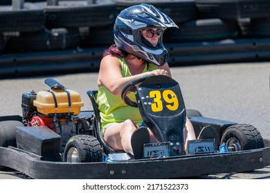 Saint-Zotique, Canada - June 25, 2022: An Adult Woman Wearing A Helmet Races Around An Outdoor Go Kart Track 