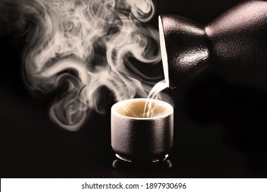 Sake, pouring traditional distilled and fermented alcohol from Japan, served hot. Black background with copy space