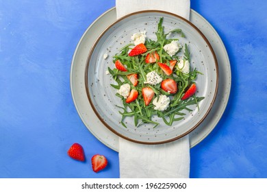 Salad With Arugula, Strawberries, Ricotta And Chia Seeds. Overhead, On A Bright Blue Background, A Copy Of The Space