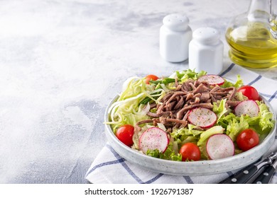 Salad with beef tongue and fresh vegetables on a plate. Text space