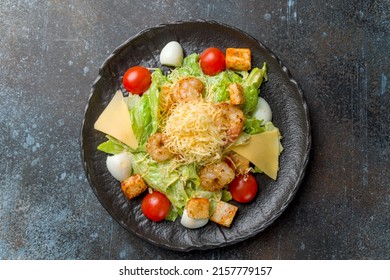 Salad Caesar With Shrimps On Black Plate On Dark Blue Stone Table Top View