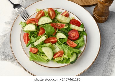 Salad of chopped cherry tomatoes and cucumbers in a white round plate on the table, healthy food. Top view - Powered by Shutterstock