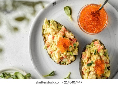 salad with crab and avocado. the salad is laid out in half an avocado and decorated with red caviar, flatlay