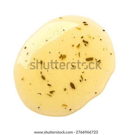 Salad dressing with herbs dropping, creating a textured yellow splash on white