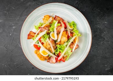 Salad With Fried Chiken And Bacon On A Black Background