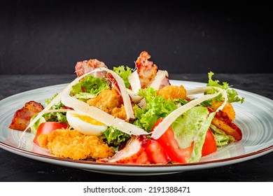 Salad With Fried Chiken And Bacon On A Black Background