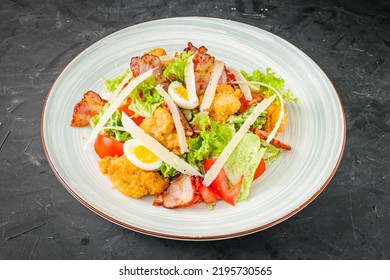 Salad With Fried Chiken And Bacon On A Black Background