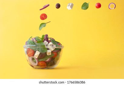 Salad Ingredients, Including Feta Cheese, Kalamata Olives And Tomatoes Falling Into A Bowl