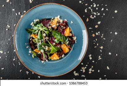 Salad With Liver, Arugula, Orange, Spinach And Almonds On Plate Over Dark Stone Surface. Healthy Food Concept. Top View