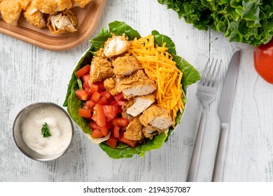 Salad Made With Fried Chicken Tender Cubes, Tomato, Cheese, Lettuce And Ranch Dressing. Top Down Shot.