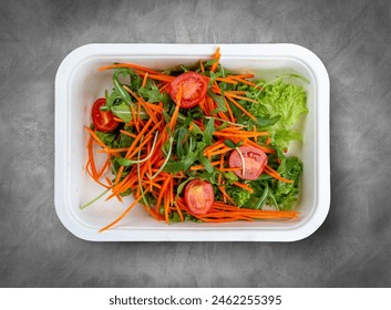 Salad mix (greens, carrots and cherry tomatoes). Healthly food. Takeaway food. Top view, on a gray background. - Powered by Shutterstock