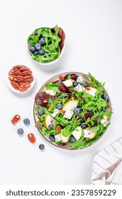 Salad with Pear, Arugula, Blue Cheese, Nuts and Blueberry, Delicious Fresh Salad on Bright Background - Shutterstock ID 2357859229