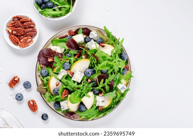 Salad with Pear, Arugula, Blue Cheese, Nuts and Blueberry, Delicious Fresh Salad on Bright Background