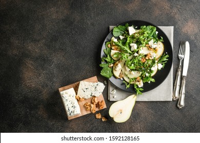 Salad Of Pear, Blue Cheese, Arugula And Nuts With Spicy Dressing On A Dark Background. Top View Free Copy Space. Healthy Eating.