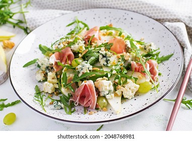 Salad Of Pear, Blue Cheese, Grape, Prosciutto, Arugula And Nuts With Spicy Dressing On A Light Background. Healthy Eating.