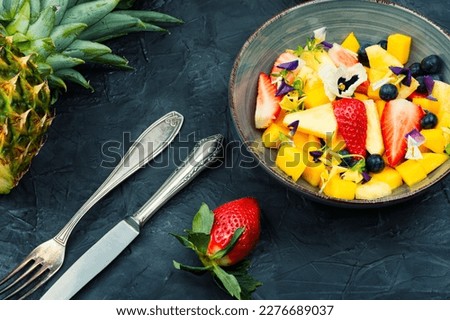 Salad of pineapple, strawberries and berries, decorated with edible flowers. Clean ealthy eating