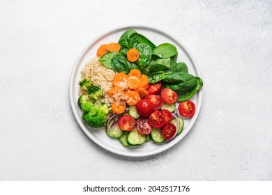 Salad With Quinoa, Spinach, Broccoli, Tomatoes, Cucumbers And Carrots, Served On Plate With White Background And Copy Space. Clean Healthy Food Concept