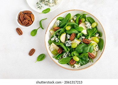 Salad of spinach, pear, grape, pecan and gorgonzola cheese with lemon dressing. Healthy food, diet. Top view. - Powered by Shutterstock