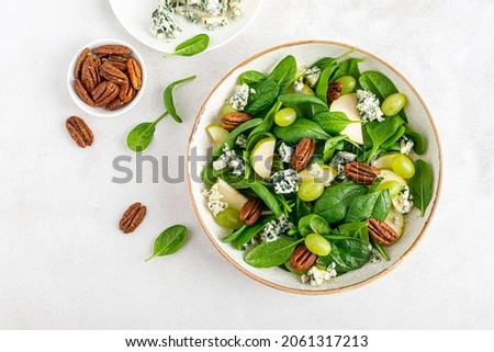 Salad of spinach, pear, grape, pecan and gorgonzola cheese with lemon dressing. Healthy food, diet. Top view.