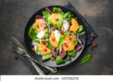 Salad with tangerines, mozzarella, herbs, pomegranate seeds and nuts on a dark background. Top view. - Powered by Shutterstock