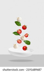 Salad with tomatoes, mozzarella and basil on a white plate. Flying ingredients, Levitation. - Shutterstock ID 2191689687