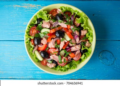 Salat mit Gemüse und Thunfisch auf rustikalem, blauem Holztisch. Draufsicht.