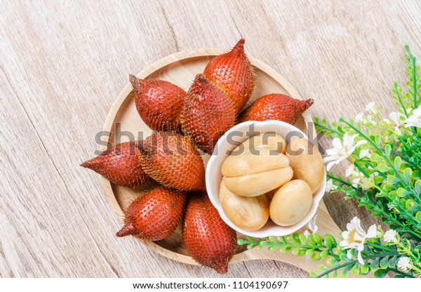 Salak Palm , waive or snake fruit in wooden dish\
on the table.