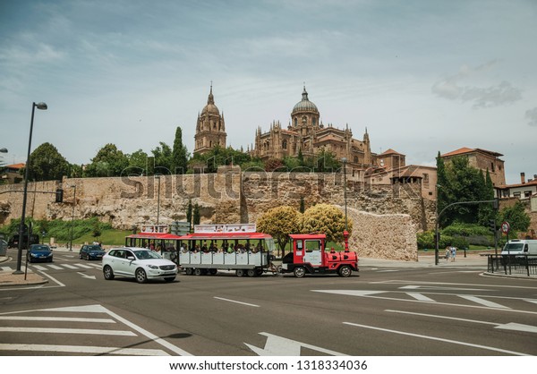 Salamanca, Spain - July 21, 2018. Dome and steeple\
from New Cathedral and wall on a street cross road at Salamanca.\
This lovely medieval town is one of the most important university\
cities in Spain.