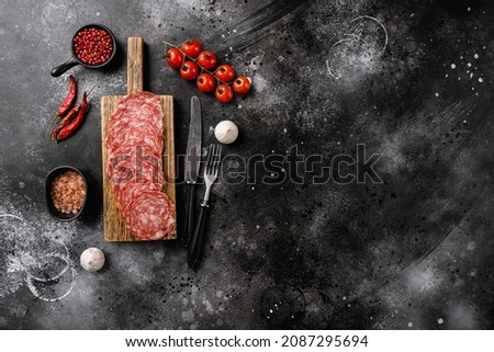 Salami Milano sliced sausage set, on black dark stone table background, top view flat lay, with copy space for text