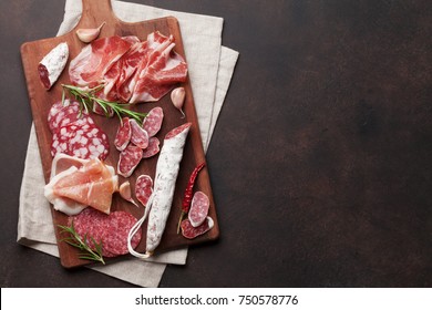 Salami, sliced ham, sausage, prosciutto, bacon. Meat antipasto platter on stone table. Top view with copy space