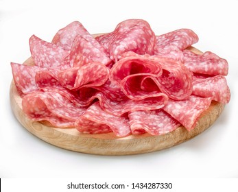 Salami slices on a round wooden cutting board, isolated on white
