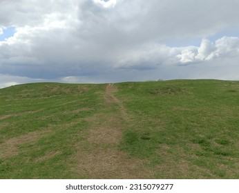 Salduve hill during cloudy day. Small hill. Grass is growing on hill. Staircase leading to the top. Cloudy day with white and gray clouds in sky. Nature. Salduves piliakalnis. - Powered by Shutterstock