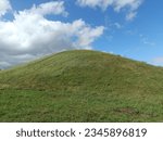 Salduve hill during sunny day. Small hill. Grass is growing on hill. Staircase leading to the top. Sunny day with white and gray clouds in sky. Nature. Salduves piliakalnis.