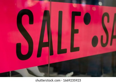 Sale advertisement at a clothing store. Bright pink poster sign with the word Sale at the entrance. Shop window on the outside of fashion store display poster sticker. - Shutterstock ID 1669235923