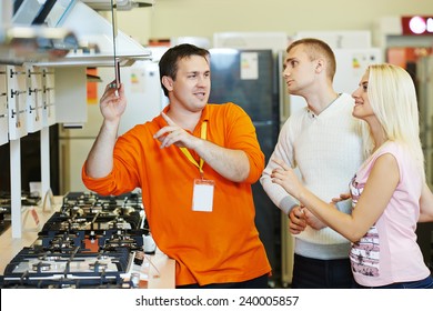 Sale Assistant Demonstrating Cooker Stove To Young Family In Home Appliance Shopping Mall Supermarket