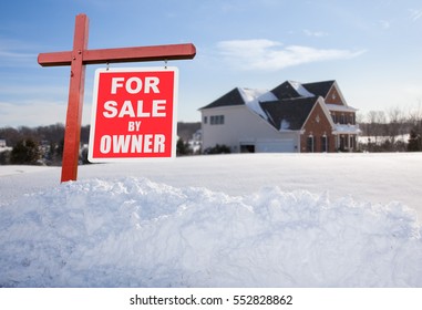 For Sale By Owner Real Estate Sign In Front Of Large Brick Single Family House In Expansive Snow Covered Yard In Mid Winter