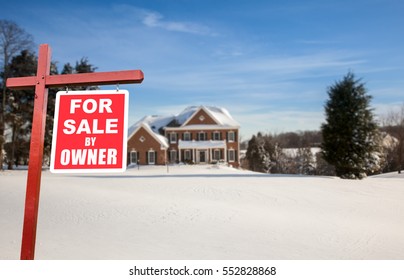 For Sale By Owner Real Estate Sign In Front Of Large Brick Single Family House In Expansive Snow Covered Yard In Mid Winter