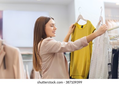 Sale, Clothes , Shopping, Fashion And People Concept - Happy Young Woman Choosing Between Two Shirts In Mall Or Clothing Store