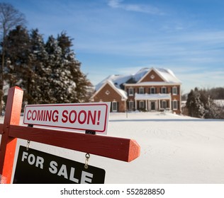 For Sale And Coming Soon Realtor Sign In Front Of Large Brick Single Family House In Expansive Snow Cover Yard In Mid Winter