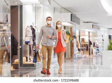 conceito de venda, consumismo e pandemia - jovem casal feliz usando máscara médica protetora facial para proteção contra doenças virais com sacolas de compras andando no shopping