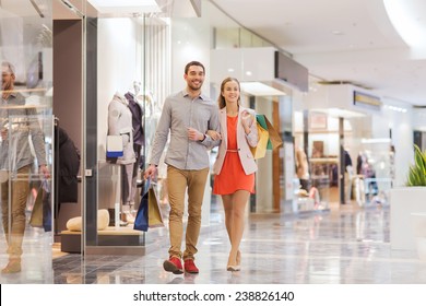 Sale, Consumerism And People Concept - Happy Young Couple With Shopping Bags Walking In Mall