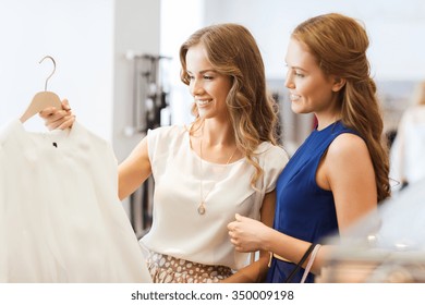 Sale, Consumerism And People Concept - Happy Young Women With Shopping Bags Choosing Clothes At Clothing Shop