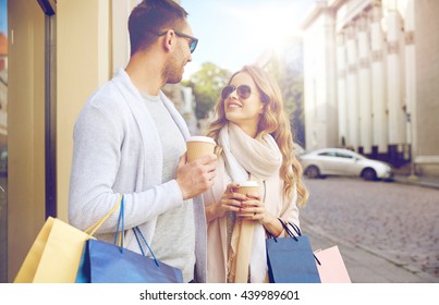 Sale, Consumerism And People Concept - Happy Couple With Shopping Bags And Coffee Paper Cups At Shop Window In City