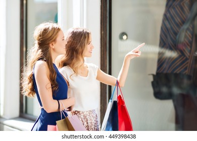 Sale, Consumerism And People Concept - Happy Young Women With Shopping Bags Pointing Finger To Shop Window In City